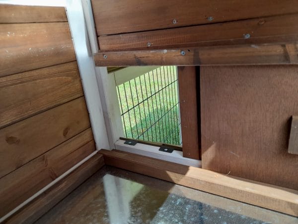 Interior of large brown rabbit hutch. showing metal lining on floor